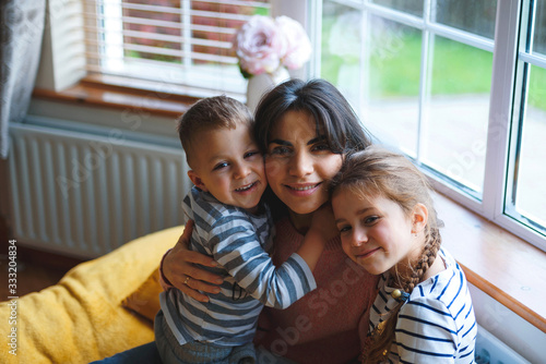 mother hugging son and daughter at home