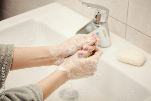 Female washing hands under the running water using natural soap