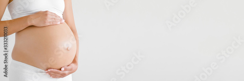 Woman hands touching naked belly. Isolated on light gray background. Emotional loving pregnancy time - 37 weeks. Baby expectation. Side view. Banner. Empty place for text, quote, saying. Closeup.