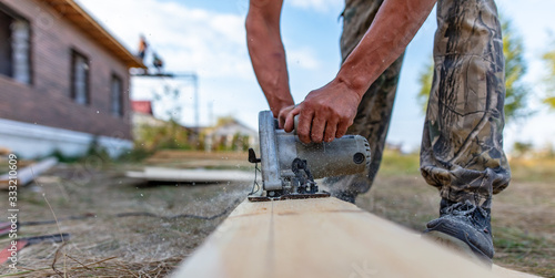 A worker saws a wooden beam.