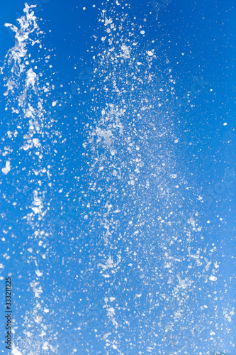 Splashing water from a fountain on a background of blue sky