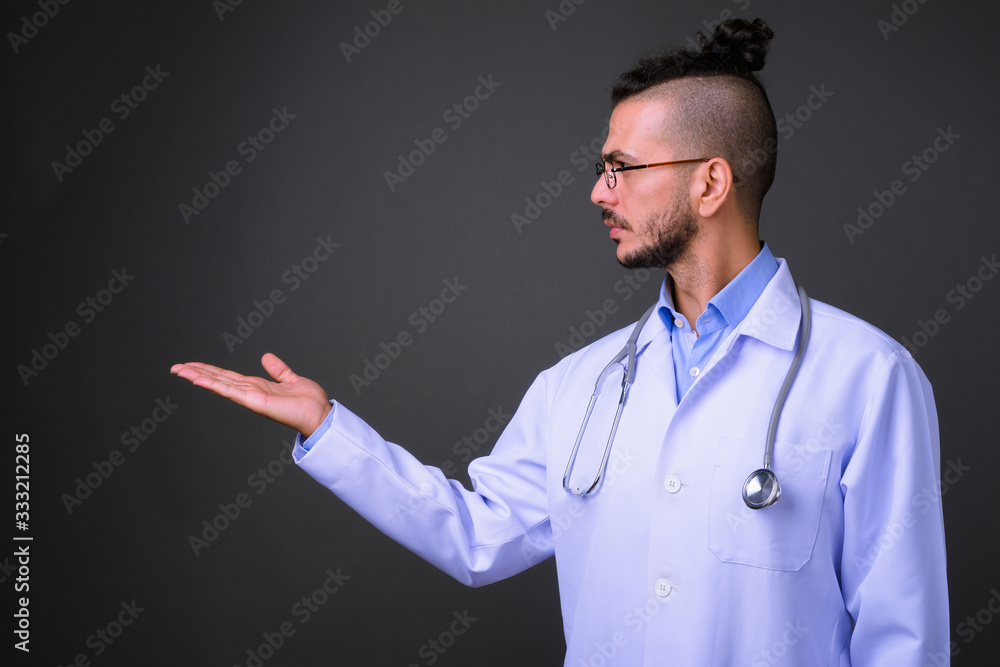 Profile view of handsome bearded Turkish man doctor showing something Profile view of handsome bearded Turkish man doctor showing something