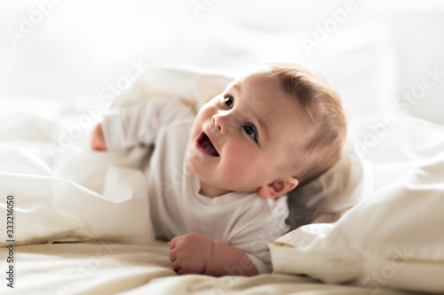 Cute happy 7 month baby girl lying on bed