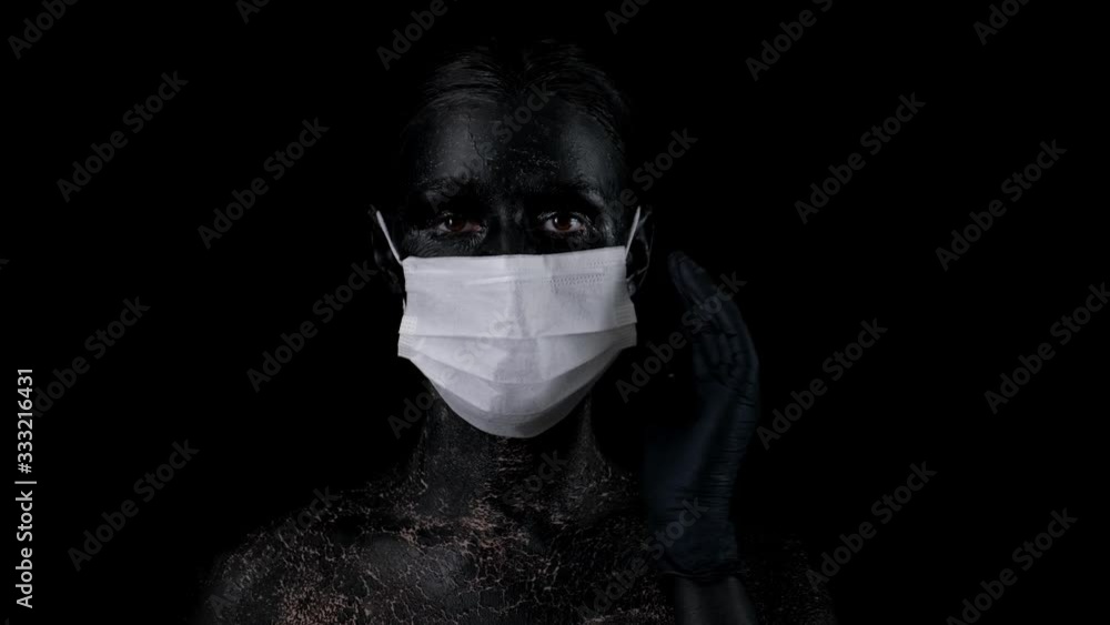 woman with black colord face wearing medical mask on blacvk background to protect against the coronavirus. Novel coronavirus 2019-nCoV, pandemic. woman with black colord face wearing medical mask on blacvk background to protect against the coronavirus. Novel coronavirus 2019-nCoV, pandemic.