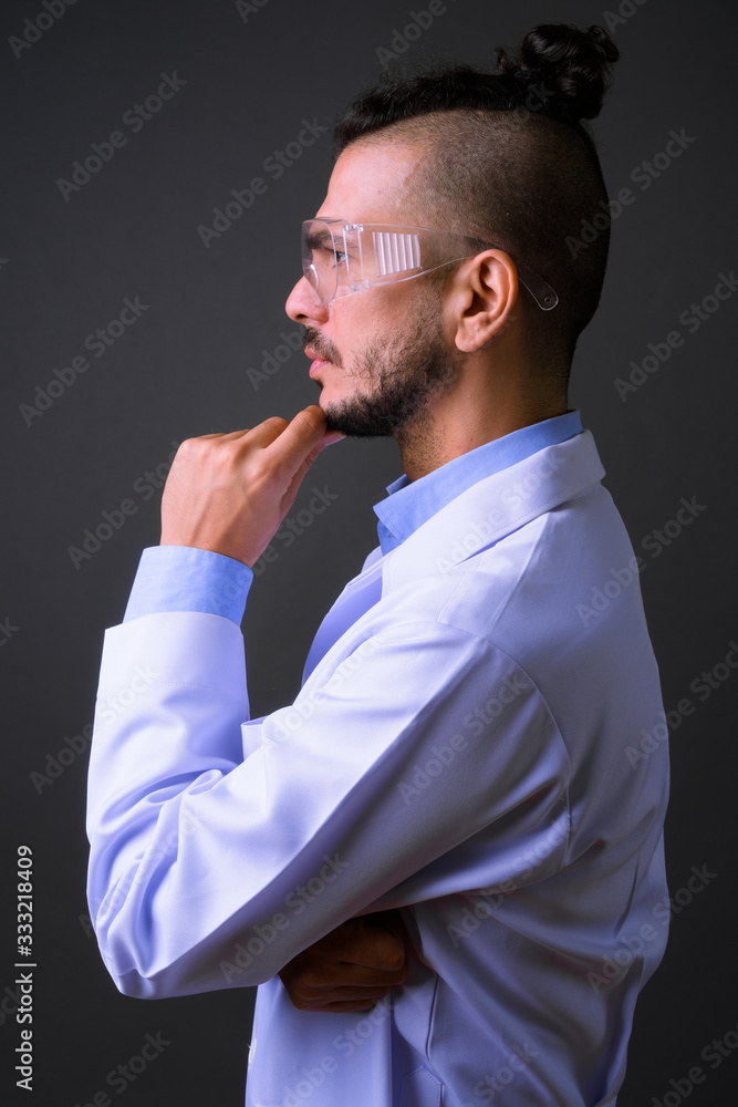 Profile view of handsome bearded Turkish man doctor as scientist thinking Profile view of handsome bearded Turkish man doctor as scientist thinking