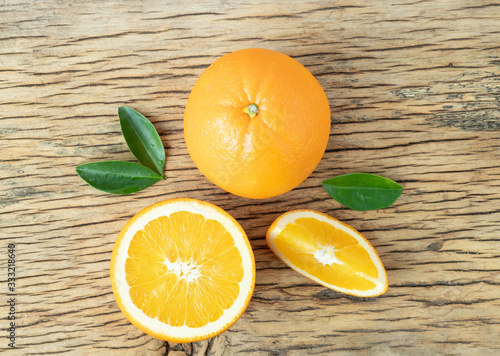 Top view of orange fruit cut half and slice with green leaf on wood background