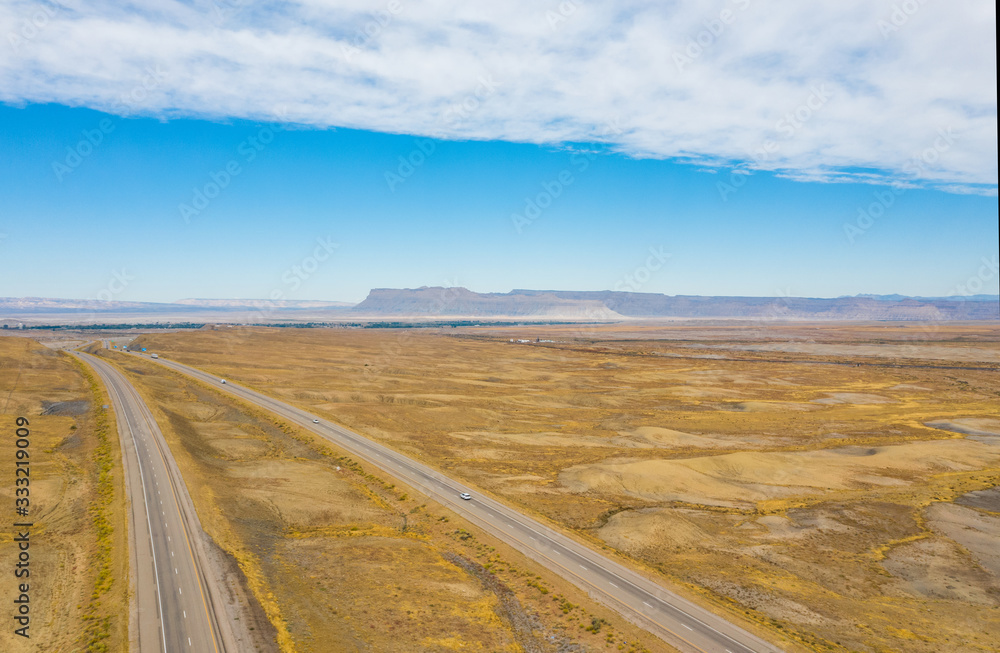 Aerial top view of nature landscape. Blue sky with clouds, highway road, mountains, on background. USA country