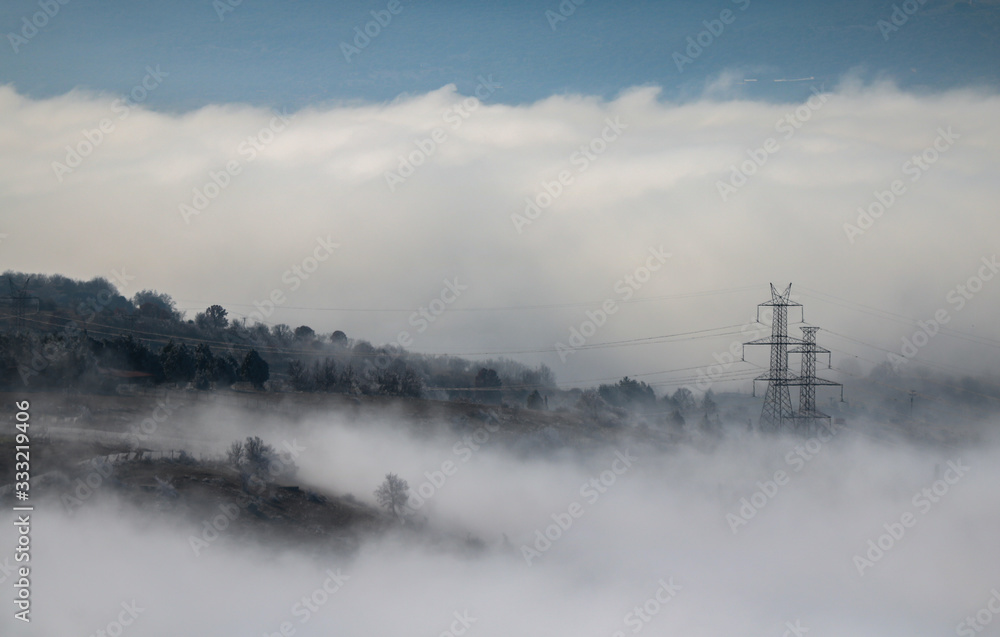 Foggy mountains for background. Electric pylon between mist and clouds. Forest at winter time. Foggy mountains for background. Electric pylon between mist and clouds. Forest at winter time.
