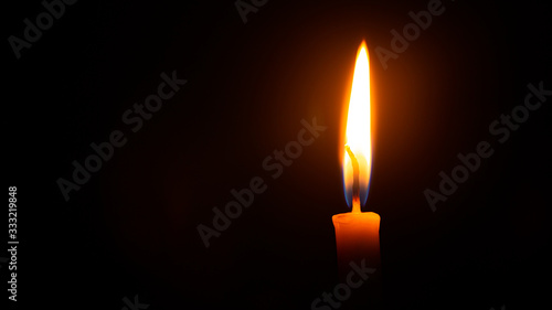 Close up single candle light and flame on black background