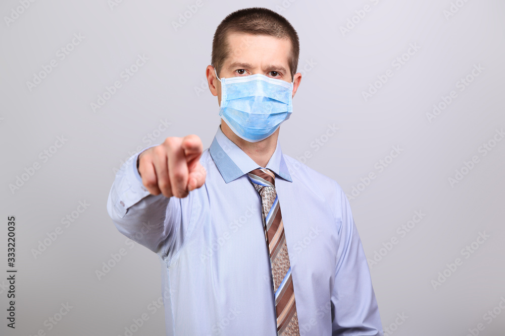 A man in a light shirt, tie and medical mask pokes his finger into a cell isolated A man in a light shirt, tie and medical mask pokes his finger into a cell isolated