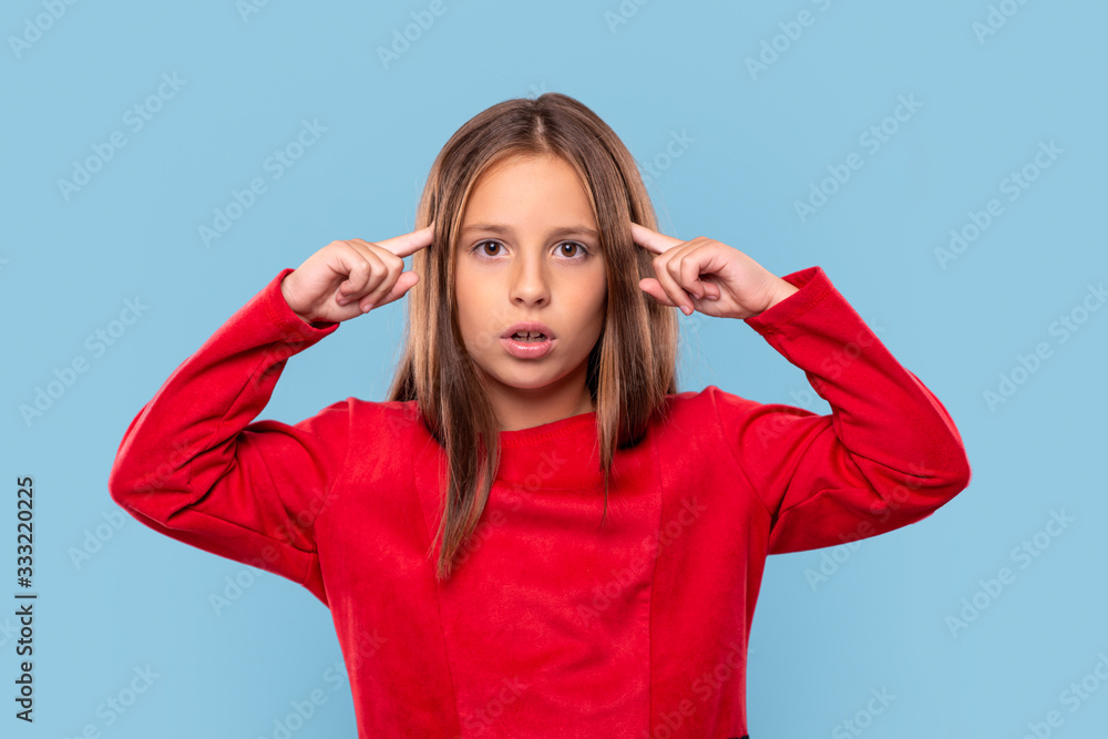 Fototapeta premium A young girl experiences stress against blue background with copy space in studio.