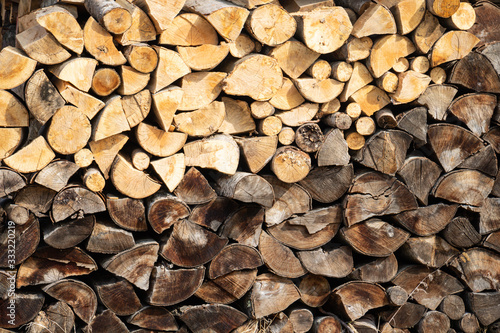 Firewood storage concept. Natural sawn wood stacked in row, texture. Stacks of chopped logs as background. Wallpaper.