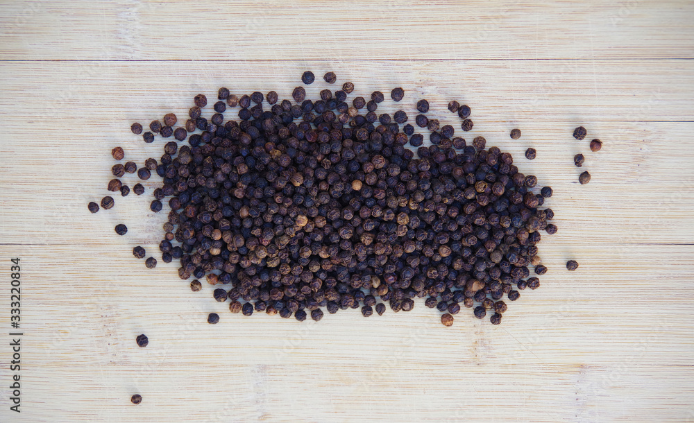 High angle close-up view of a bamboo board with a pile of black peppercorns High angle close-up view of a bamboo board with a pile of black peppercorns