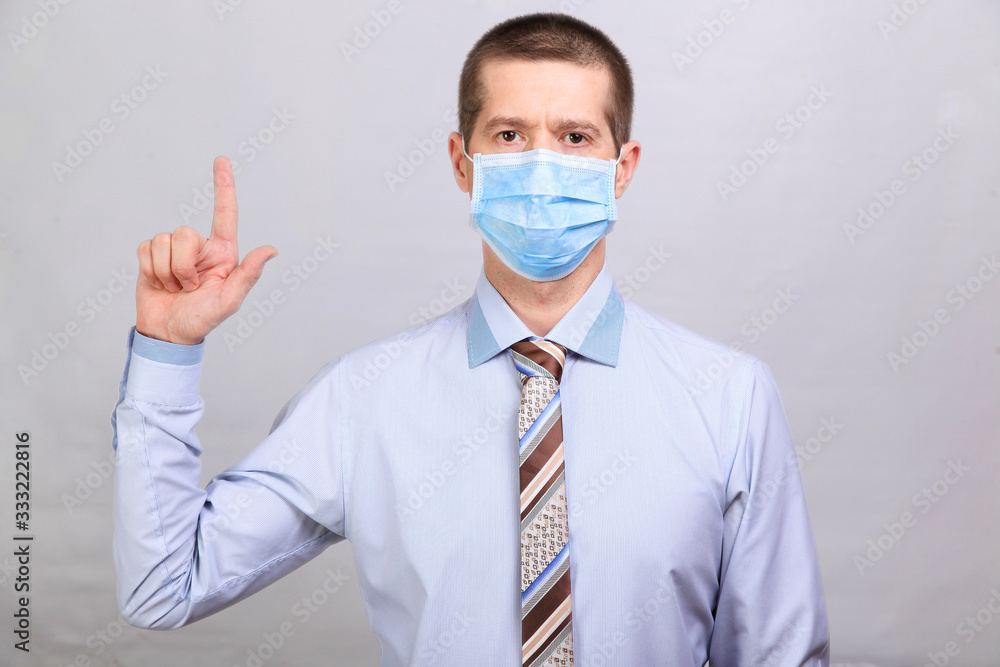 Man in shirt and medical mask shows finger in up, isolated