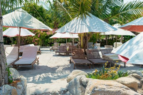 White sun umbrellas and sunbeds on a sandy beach during the day