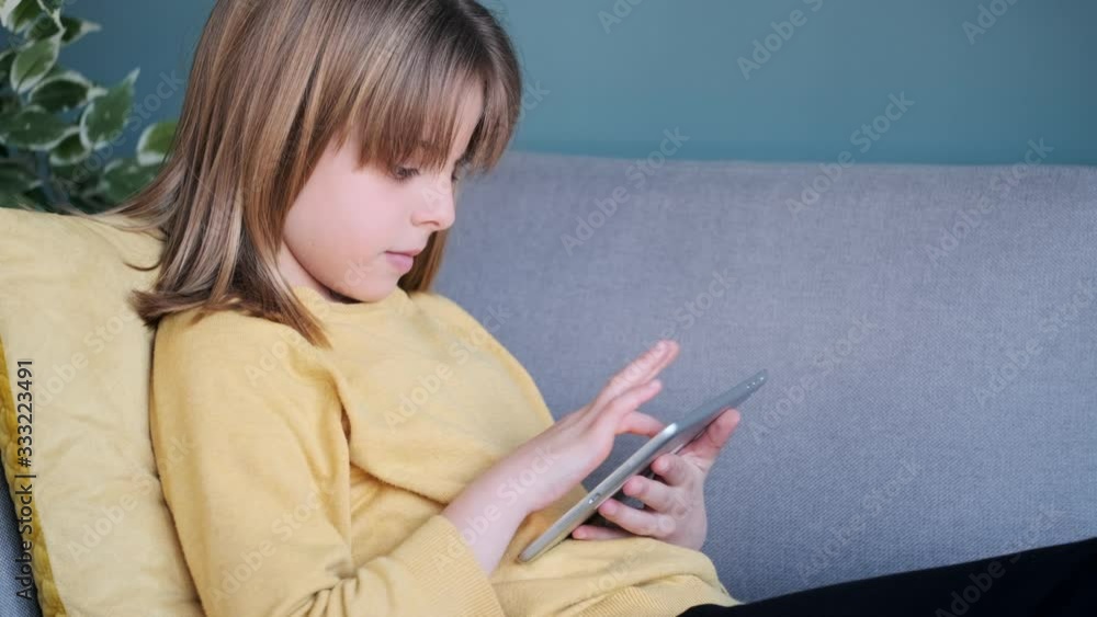 Video of little girl using her digital tablet while sitting on sofa at home. Video of little girl using her digital tablet while sitting on sofa at home.