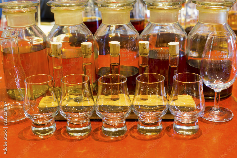 Whisky tasting setup with numbered sampling glasses, beaker and bottles on display Whisky tasting setup with numbered sampling glasses, beaker and bottles on display