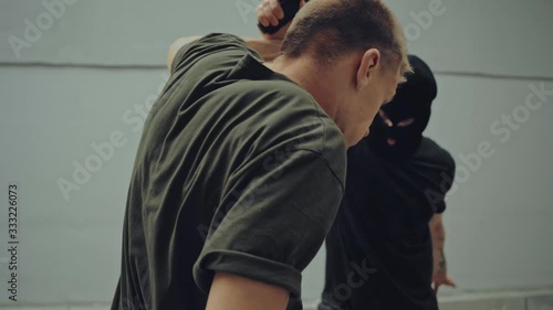 gangster in sky mask pointing with gun and fighting with man