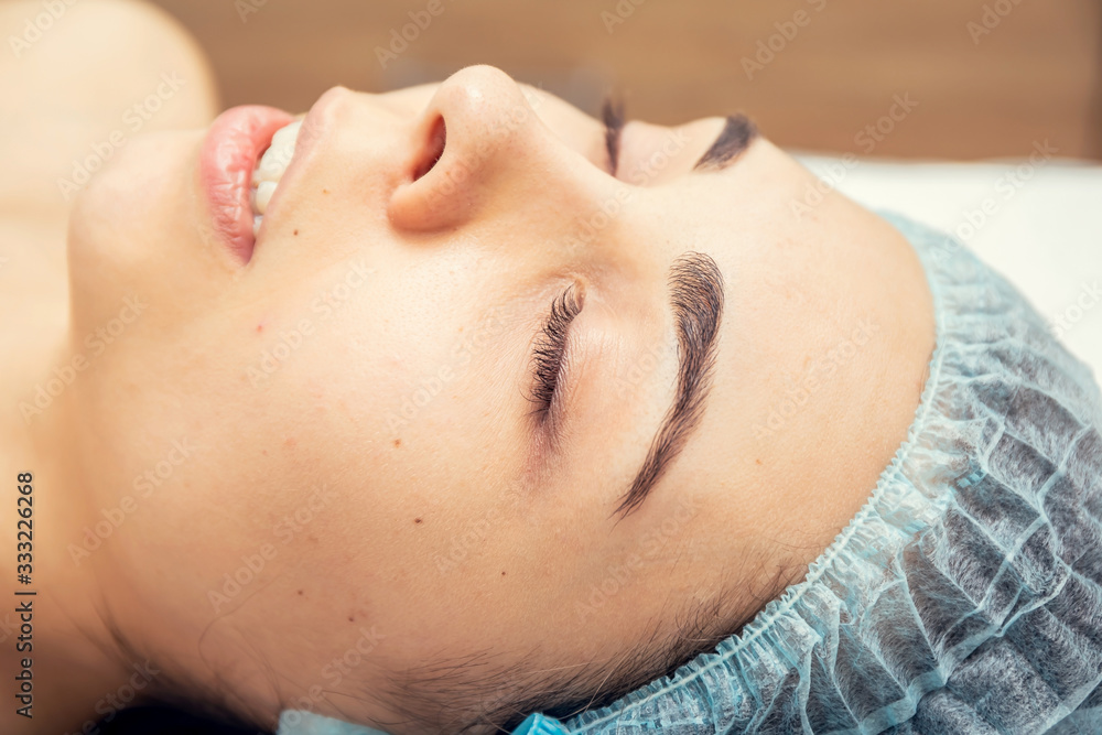 Beautiful young woman getting a facial massage with her eyes closed at the Spa.