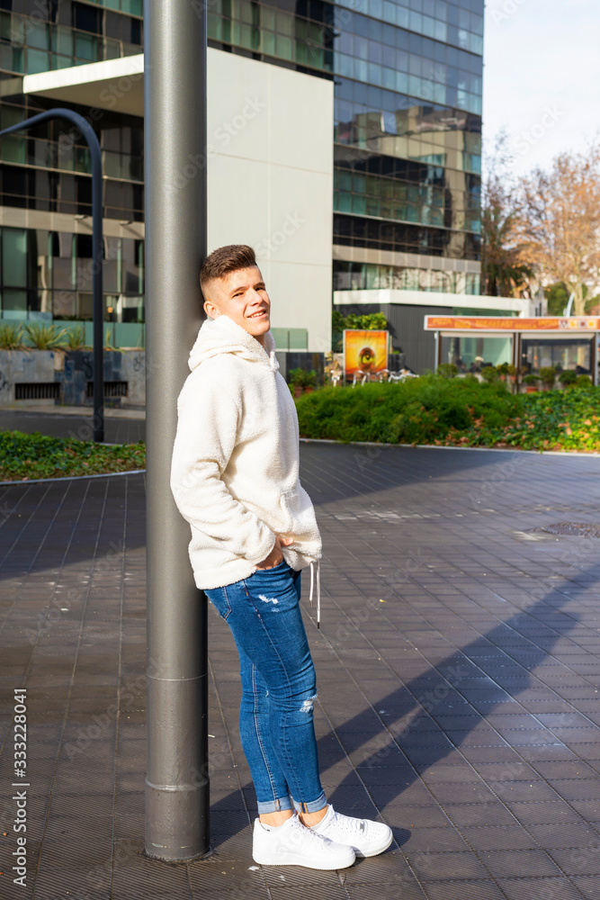 Portrait of young male with hands on pocket leaning on pole outside