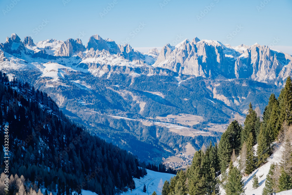 Sunny winter landscape at Ski Area in Dolomites, Italy - Alpe Lusia. Ski resort in val di Fassa near Moena. Winter Dolomites and blue sky. Aerial view on ski slopes