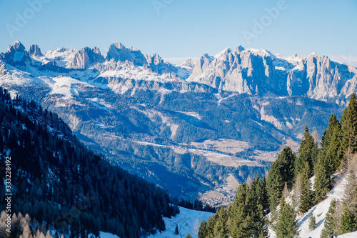 Sunny winter landscape at Ski Area in Dolomites, Italy - Alpe Lusia. Ski resort in val di Fassa near Moena. Winter Dolomites and blue sky. Aerial view on ski slopes © Alexey Oblov