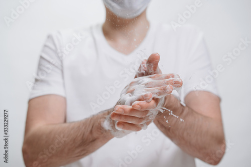 Young man in protective mask washing hands with soap as anti Coronavirus protection, hygiene to stop spreading coronavirus. COVID-19 and sanitariness content. White background