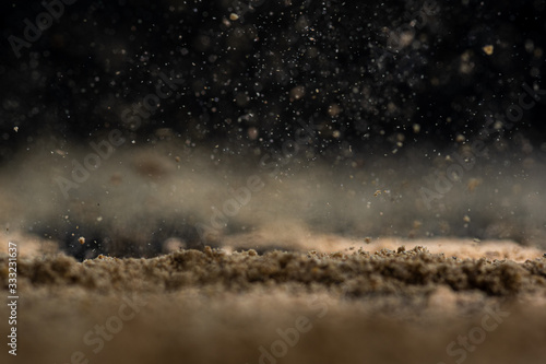 ground ginger powder on the tip of a knife and on glass on a black background