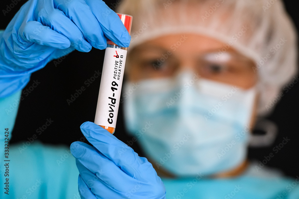Woman in protective suit hold test tube with positive result infected with coronavirus COVID - 19. Woman in protective suit hold test tube with positive result infected with coronavirus COVID - 19.