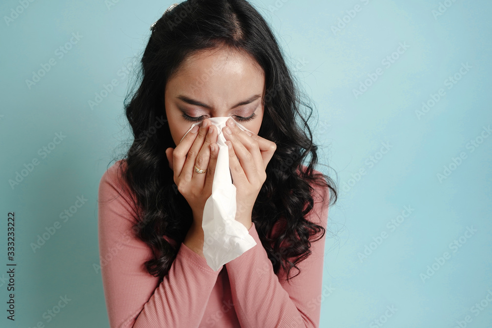 Asian teenage woman with flu corona virus covid-19 coronavirus outbreak. sick young woman blowing her nose isolated on blue background. Sickness and illness concept. Asian teenage woman with flu corona virus covid-19 coronavirus outbreak. sick young woman blowing her nose isolated on blue background. Sickness and illness concept.