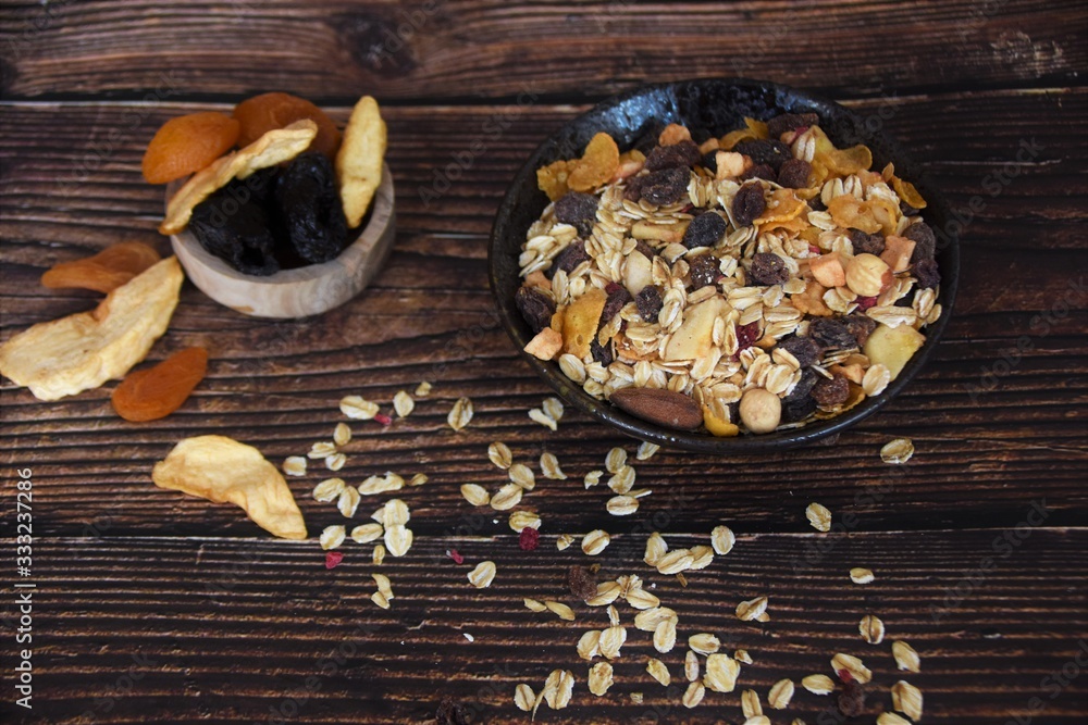muesli with dried fruits in a black bowl on a wooden table muesli with dried fruits in a black bowl on a wooden table
