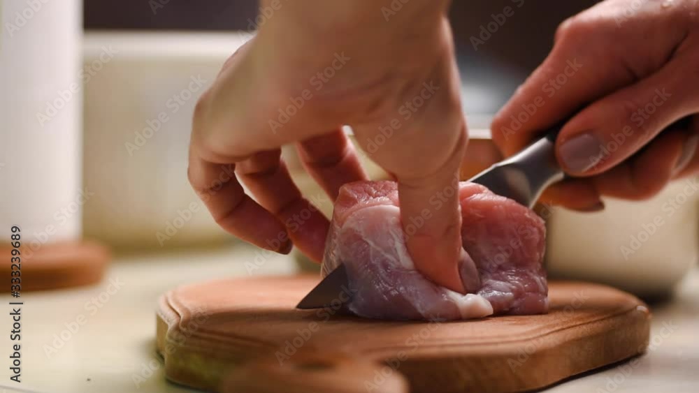 Female hands with kitchen knife cut into pieces from pork meat. Female hands with kitchen knife cut into pieces from pork meat.