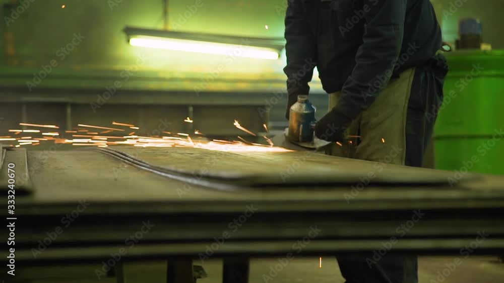 Industrial Worker with Hand Grinder on a Plant. Metal Polishing with Hand Sander with a Polishing Disk Industrial Worker with Hand Grinder on a Plant. Metal Polishing with Hand Sander with a Polishing Disk