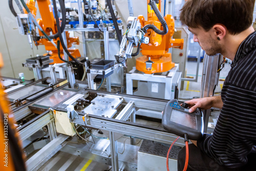 Tablou pe pânză Engineer setting up automatic robot arms in smart factory, automotive industry,