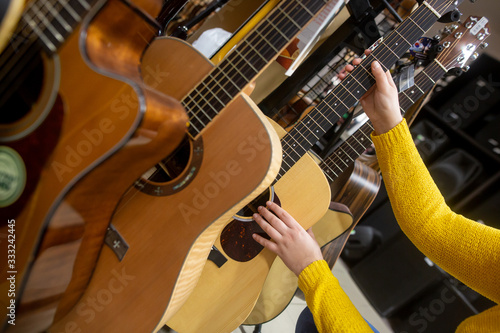 Woman choosing a new guitar in instrument shop for her lovely hobby or leisure time, shopping concept