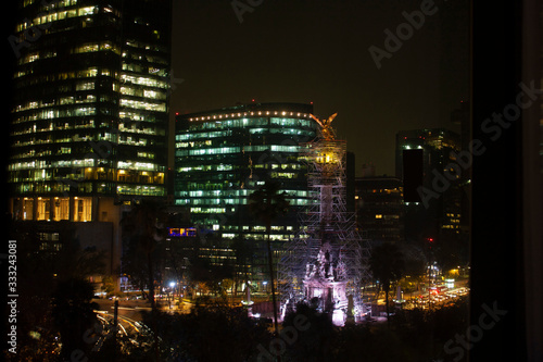 Streets of Mexico City at night painted with golden lights illuminating the buildings in the city with a city landscape