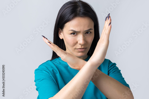 Girl disapproving with no crossing hands sign make negation gesture. Portrait of pretty woman on grey background