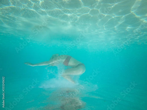 Under water photo of a woman in bikini diving in turquoise sea w © MexChriss