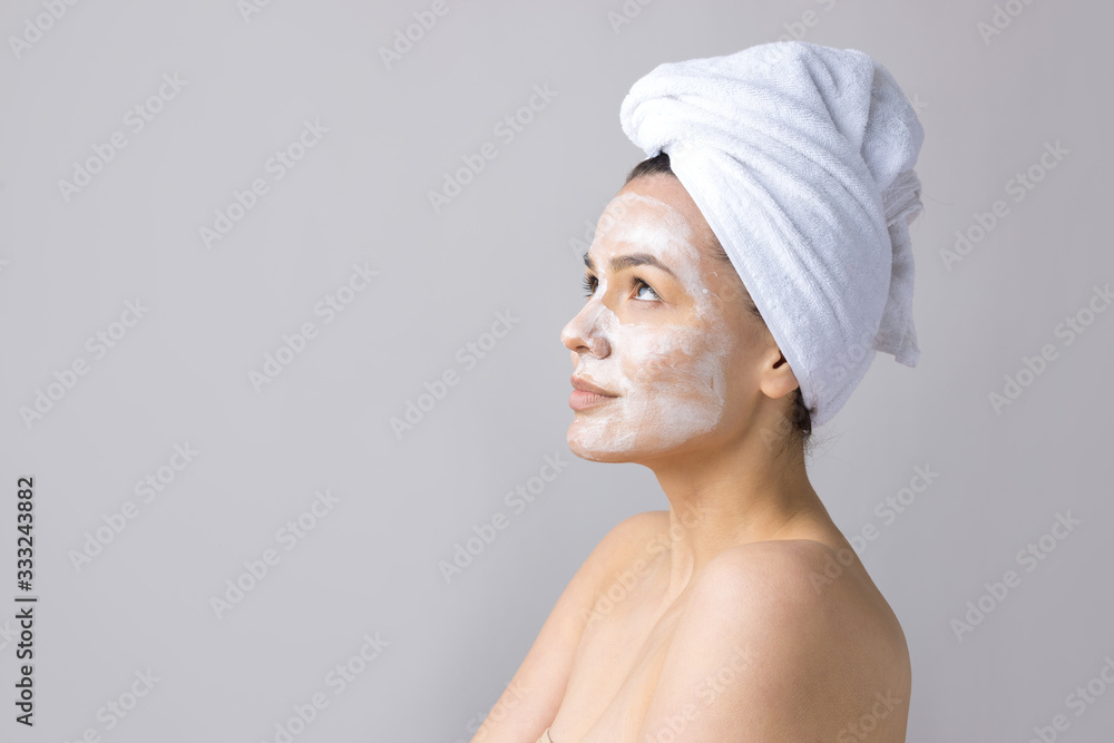 Beauty portrait of woman in white towel on head applies cream to the face. Skincare cleansing eco organic cosmetic spa relax concept. Beauty portrait of woman in white towel on head applies cream to the face. Skincare cleansing eco organic cosmetic spa relax concept.