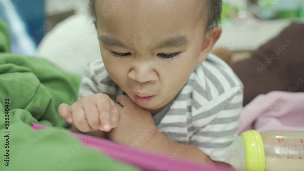 Baby boy with a bottle of milk Look at the tablet Then slide the tablet to play on the bed Baby boy with a bottle of milk Look at the tablet Then slide the tablet to play on the bed
