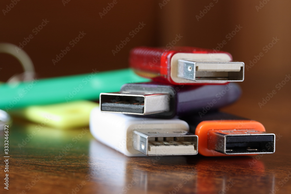 Information storage devices with usb connector with cases of various colors on a brown wooden table Information storage devices with usb connector with cases of various colors on a brown wooden table