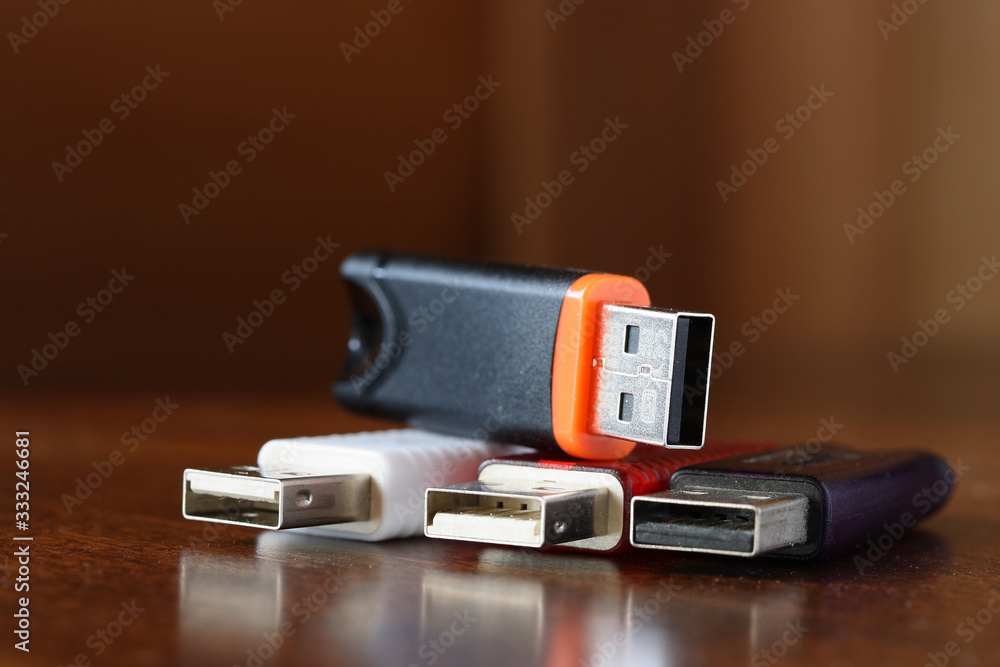 Information storage devices with usb connector with cases of various colors on a brown wooden table