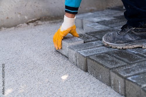 Workers lay paving tiles, construction of brick pavement, close up architecture background stock photo...