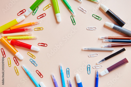 Colored markers thin thick red yellow green pink blue purple blue black gray paper clips. Stationery the colors of the rainbow are on the table , light background