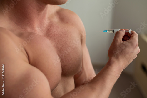 Close-up of a naked male torso. Unrecognizable shirtless bodybuilder man puts himself an injection of testosterone. Faceless athlete takes dope.