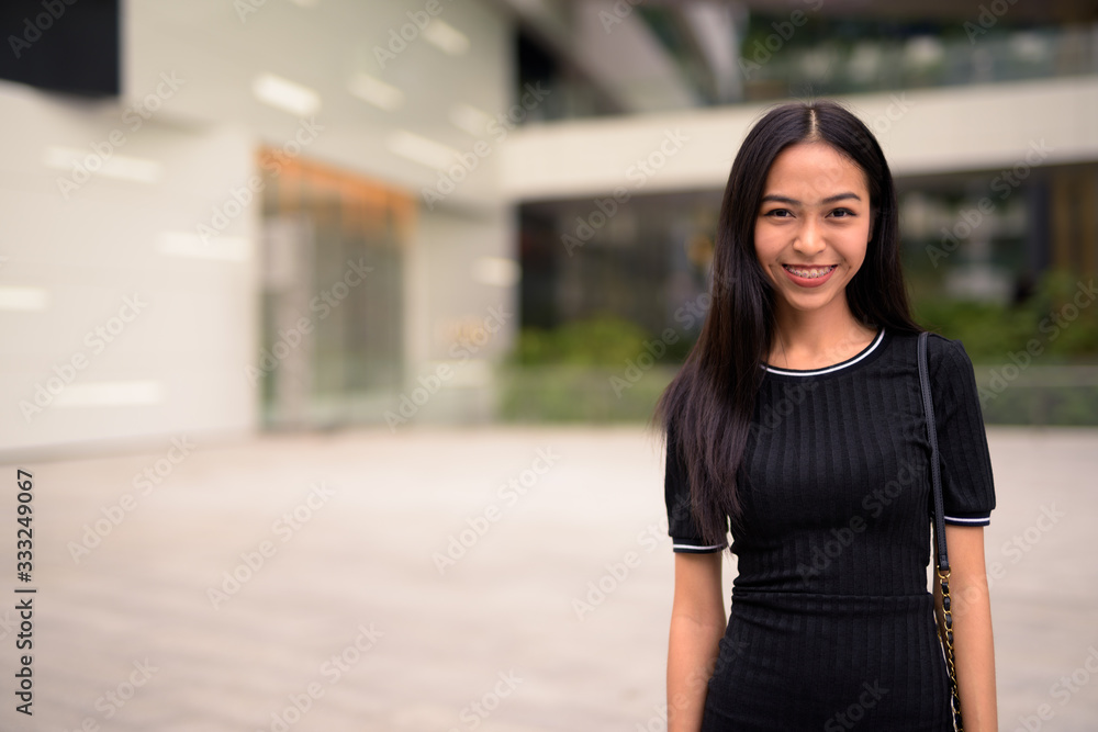 Fototapeta premium Happy young beautiful Asian tourist woman at the mall outdoors