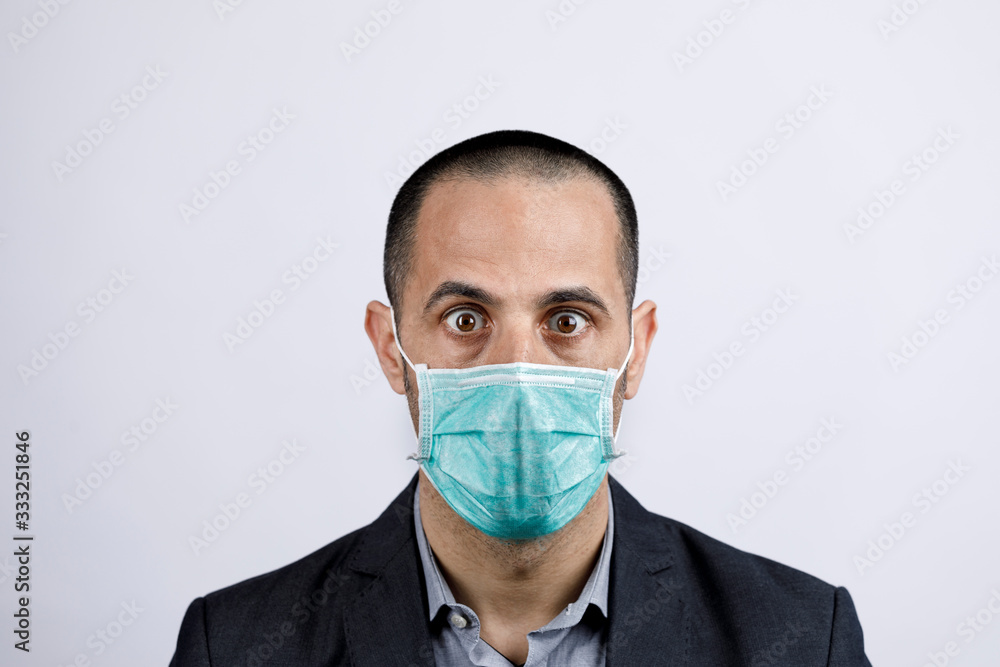 Uomo in giacca e camicia con mascherina protettiva, guarda stupito, isolato su sfondo bianco Uomo in giacca e camicia con mascherina protettiva, guarda stupito, isolato su sfondo bianco