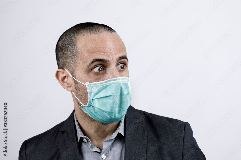 Uomo in giacca e camicia con mascherina protettiva, guarda con espressione impaurita , isolato su sfondo bianco Uomo in giacca e camicia con mascherina protettiva, guarda con espressione impaurita , isolato su sfondo bianco