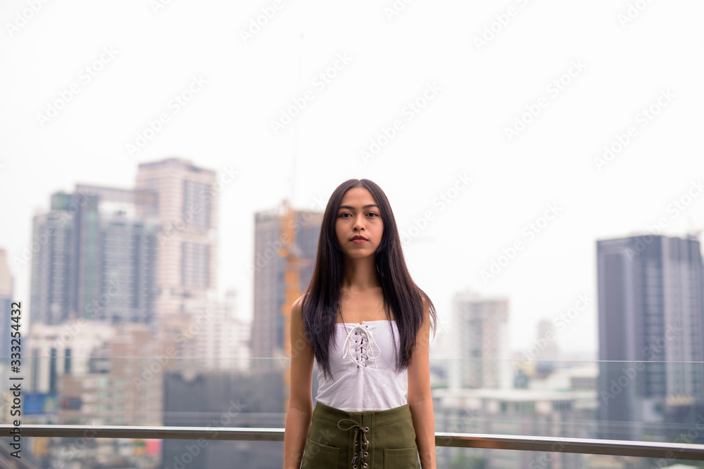 Young beautiful Asian tourist woman against view of the city