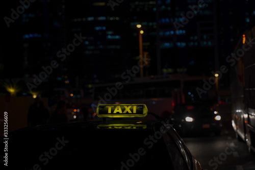 yellow taxi sign on cab car at evening or night in the city street.